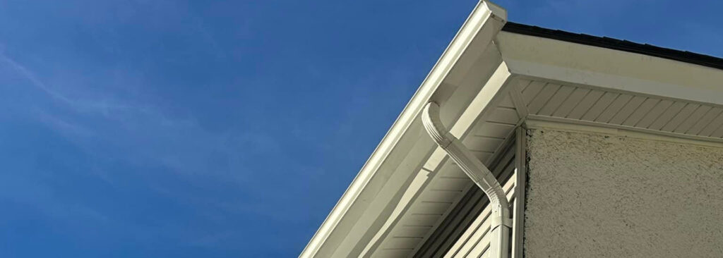 Gutter system on a residential home under a clear blue sky, showcasing the importance of proper installation and maintenance for effective water management.