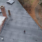 Aerial view of a flat EPDM roof with a person walking, showcasing roofing materials and insulation relevance for commercial buildings in Pittsburgh's climate.