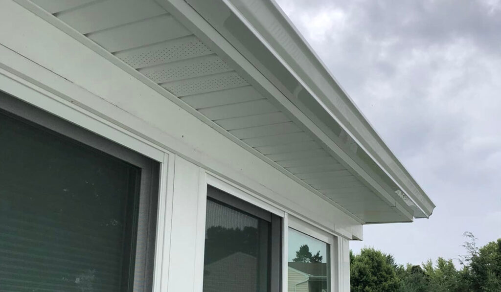 White seamless gutters installed on a residential home, showcasing the roofline and downspout area, emphasizing proper water flow management and home exterior solutions.