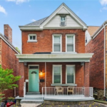 Victorian-style home in Central Northside, Pittsburgh, featuring a brick facade, front porch with seating, and a distinctive gable roof, reflecting the historical architecture and community commitment to preservation.