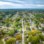 Aerial view of a suburban neighborhood in McCandless, showcasing residential homes surrounded by trees, emphasizing the importance of roof inspections and repairs after storms.