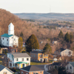 Aerial view of residential homes in Ross Township with a church steeple and hills in the background, highlighting community aspects relevant to roofing and storm damage discussions.