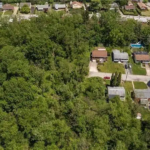Aerial view of residential homes surrounded by dense greenery, highlighting the importance of gutter maintenance for water protection in Pine Township.