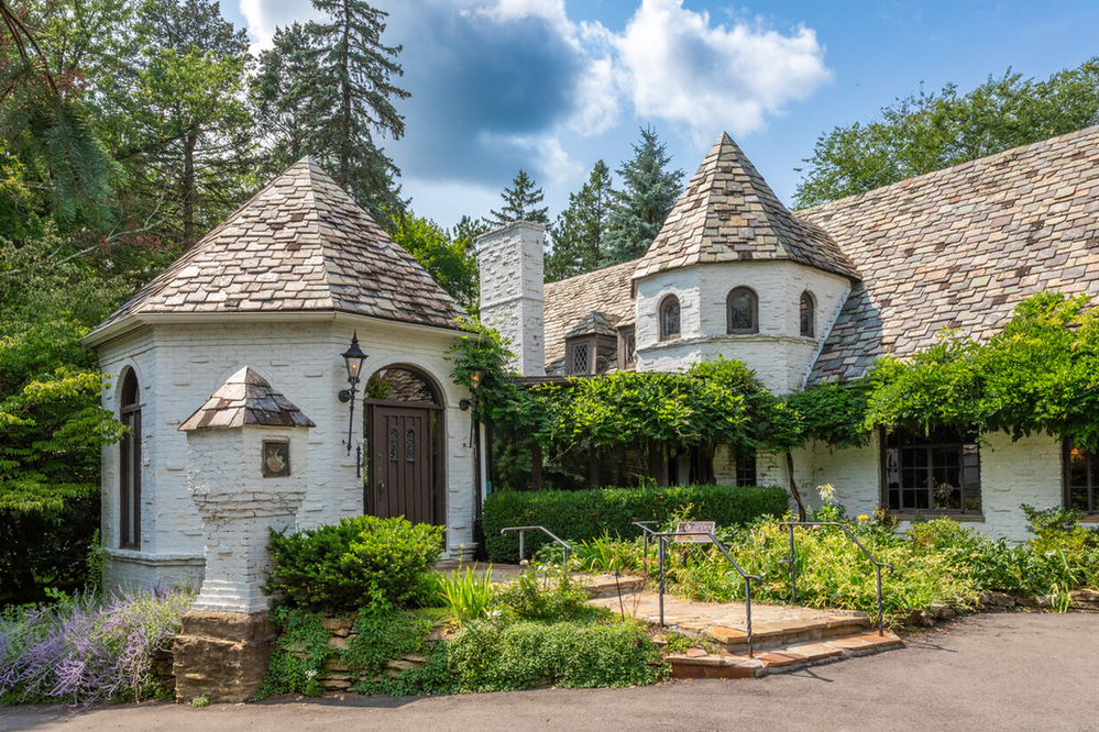 Charming residential home in Moon Township featuring a unique turreted design, durable slate roof, and lush landscaping, illustrating ideal roofing aesthetics for local weather resilience.