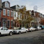 Row of residential houses with parked cars along the street, representing a neighborhood in Pittsburgh's Spring Garden area, relevant to roofing and wildlife protection tips.