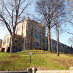 Historic building on a hillside surrounded by trees, showcasing architectural features relevant to roofing maintenance in Pittsburgh.