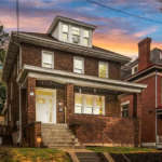 Brown brick home with a welcoming entrance and large windows, showcasing architectural charm in Pittsburgh's Spring Hill-City View neighborhood, emphasizing siding options for enhancing curb appeal.