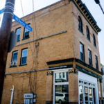 Historic brick building in Observatory Hill, Pittsburgh, showcasing architectural details and proximity to tree canopy, relevant to roofing maintenance discussions.