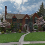 Historic home with brick exterior and decorative roofline, surrounded by lush landscaping and flowering trees, reflecting traditional architectural charm suitable for Bridgeville siding solutions.