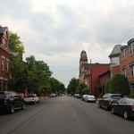 Street view in Marshall-Shadeland with residential houses, parked cars, and a church tower in the background, emphasizing local community and neighborhood for roofing services.