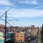 View of residential rooftops in Lawrenceville, Pittsburgh, showcasing colorful houses and utility poles under a clear blue sky, relevant to seasonal roof maintenance and inspections.