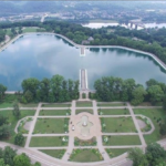 Aerial view of a landscaped park featuring a large pond, surrounding greenery, and symmetrical pathways, illustrating the importance of outdoor maintenance for homeowners in Homewood.