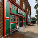 Colorful exterior of a local business in Spring Hill-City View neighborhood, featuring green and red siding, showcasing unique architectural charm and inviting outdoor seating.