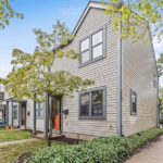 Modern two-story home in Pittsburgh with gray siding, large windows, and a well-maintained lawn, showcasing proper exterior maintenance for homeowners.