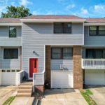 Modern multi-family home in Pittsburgh's Spring Hill-City View, featuring gray siding, a striking red front door, and brick accents, showcasing aesthetic appeal and contemporary design.