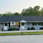 Residential building with a new gray roof, featuring a front porch and landscaping, showcasing quality roofing solutions by Malick Brothers Exteriors.