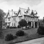 Historic Victorian-style home with intricate architectural details, surrounded by landscaped greenery, emphasizing the importance of quality roofing and exterior services.