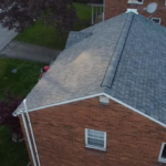 Aerial view of a residential roof showcasing quality asphalt shingles and brick exterior, reflecting Malick Brothers Exteriors' commitment to superior craftsmanship in roofing services.