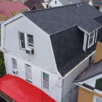 Aerial view of a house featuring a dark shingle roof, showcasing potential roofing solutions for homeowners considering metal roofing options for durability and aesthetic appeal.
