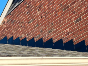 Commercial roof with visible brick wall and roofing edge, highlighting potential areas for water intrusion and the importance of timely maintenance to prevent costly damage.