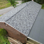 Roof featuring Atlas Pinnacle® Pristine architectural shingles in Woodland Green, showcasing durability and aesthetic appeal, complemented by brick exterior and surrounding greenery.