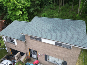 Aerial view of a residential building with a green shingle roof, surrounded by trees, illustrating sustainable roofing practices relevant to recycling and material recovery.