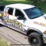 Malick Brothers Exteriors branded truck parked on a residential street, showcasing storm-proofing and roofing services.