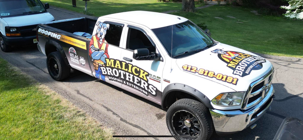 Malick Brothers Exteriors branded truck parked on a residential street, featuring bold graphics and contact information, emphasizing local roofing services in Pittsburgh.