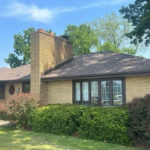 Residential home exterior featuring well-maintained siding, a brick chimney, and neatly trimmed landscaping, illustrating effective siding maintenance and curb appeal.