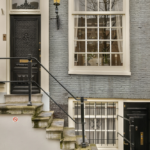 Modern home entrance with black door, decorative lantern, and stone steps, reflecting aesthetic appeal and durability for Pittsburgh roofing solutions.
