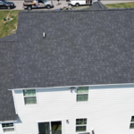 Aerial view of a home with a gray shingle roof and white siding, illustrating the importance of maintaining exterior integrity for homeowners.