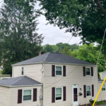 Pittsburgh home with a newly replaced roof, showcasing modern roofing materials and a well-maintained exterior, surrounded by trees and a cloudy sky.
