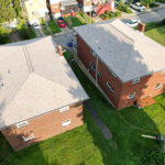 Aerial view of two residential buildings with sloped roofs, showcasing roof conditions relevant to sagging issues and the importance of regular maintenance in roofing.