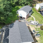 Aerial view of a residential roofing project in progress, showcasing new asphalt shingles on one roof and surrounding homes, emphasizing roofing services by Malick Brothers Exteriors.