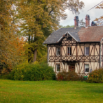 Tudor-style home with timber framing surrounded by lush greenery and autumn foliage, illustrating exterior aesthetics and potential siding options for Pittsburgh homeowners.