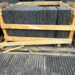 Stack of slate roofing tiles in wooden crate, showcasing durability and elegance for residential roofing solutions.
