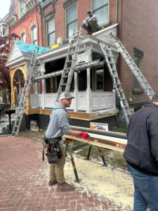 Construction workers on ladders performing roofing and exterior renovations on a historic building in Pittsburgh, showcasing local expertise in commercial roofing services.