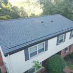 Aerial view of a recently installed dark shingle roof on a two-story home, showcasing quality workmanship by Malick Brothers Exteriors, emphasizing efficient roofing solutions.