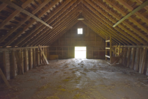 Empty attic space with wooden beams, showing potential for roof ventilation improvements and airflow, relevant to Pennsylvania homes' energy efficiency and structural integrity.