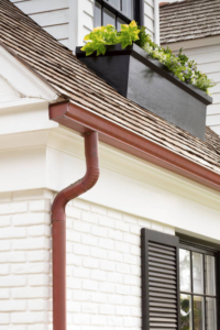 Gutter system and downspout on residential roof, showcasing proper water drainage and protection against weather elements.