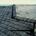 Slate roof with overlapping tiles and chimney, showcasing durability and aesthetic appeal, relevant to maintenance and longevity of roofing materials.