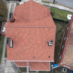 Aerial view of a residential roof featuring terra cotta shingles, showcasing the design and structure relevant to flat roofing solutions in Pittsburgh.
