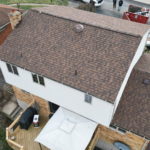 Roof featuring Atlas Pinnacle® Pristine Shingles in Coastal Granite, showcasing durability and aesthetic appeal, with surrounding residential setting and outdoor elements.