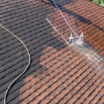 Roofing maintenance with a pressure washer cleaning a textured surface, highlighting rubber roofing suitability for Pittsburgh's weather.