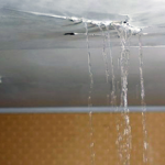 Water leaking from a ceiling, indicating potential roof damage or maintenance issues related to asphalt shingles.