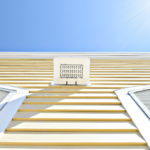 Close-up of a home's exterior siding with horizontal lines, featuring a vent and two white window frames, under a clear blue sky, emphasizing durability and weather resistance for Pittsburgh homes.