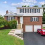 Modern home exterior in Pittsburgh featuring a mix of brick and siding, complemented by a landscaped front yard and a red car parked in the driveway, illustrating contemporary design in a historic neighborhood context.