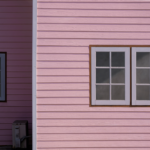 Pink siding with white trim and windows, illustrating potential siding maintenance and inspection for homeowners.