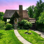 Charming home in Crafton Heights with well-maintained siding and roof, surrounded by lush greenery and a manicured lawn, emphasizing community pride in home aesthetics and preservation.