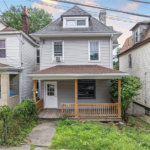 Residential home in South Side Flats featuring a new roof, modern architectural design, porch, and surrounding greenery, representing urban elegance and functionality.